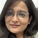 la imagen puede contener a una mujer de cabello color negro,tiene puestos unos lentes redondos y sonrie un poco. 